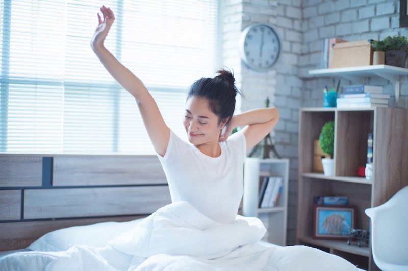 Woman waking up in bed stretching.